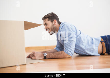 Lächelnder Mann auf der Suche in Karton Stockfoto