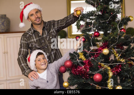 Lächelnd, Sohn und Vater schmücken den Weihnachtsbaum Stockfoto