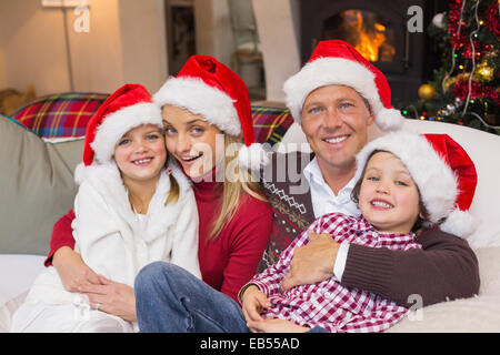 Festliche Familie in Santa Hut umarmt auf couch Stockfoto