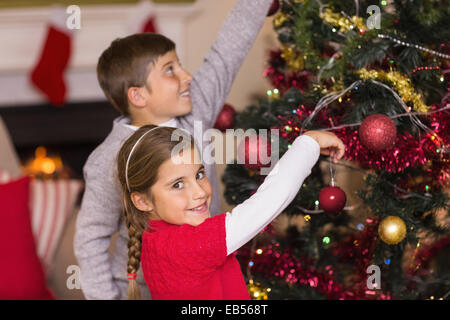 Bruder und Schwester gemeinsam den Weihnachtsbaum schmücken Stockfoto