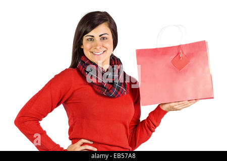 Lächelnde Brünette zeigt rote Geschenktüte Stockfoto