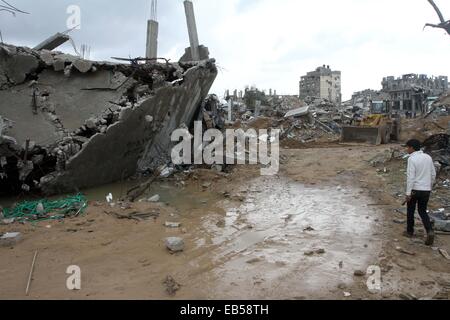 Gaza-Stadt, Gazastreifen, Palästinensische Gebiete. 26. November 2014. Ein palästinensischer Jugendlicher geht Vergangenheit Ruinen eines Hauses während der siebenwöchigen israelischen Offensive im Gazastreifen, als der Betrieb des zerstörten Ruinen begann in Shijaeya Nachbarschaft, östlich von Gaza-Stadt, 26. November 2014 entfernen. Nach der Gaza-Krieg endete am 26. August 2014 Israel ermöglichte eine kleine Menge von Baumaterial in den Gazastreifen einige Zehntausende von Häusern zerstört durch Luftangriffe und Artillerie beim Wiederaufbau zu helfen, aber hat nicht spürbar nachgelassen, die Blockade © Mohammed Asad/APA Bilder/ZUMA Draht/Alamy Live News Stockfoto