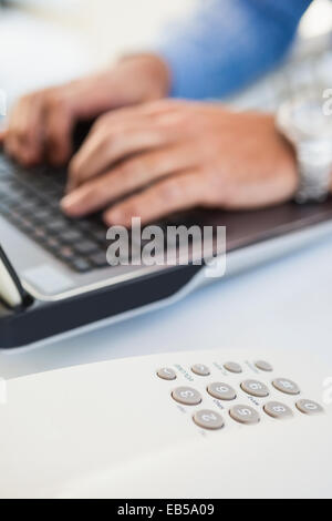 Hände des Mannes auf Laptop in der Nähe eines Telefons eingeben Stockfoto