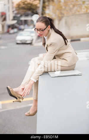 Junge Geschäftsfrau, die ihren Schuh anpassen Stockfoto
