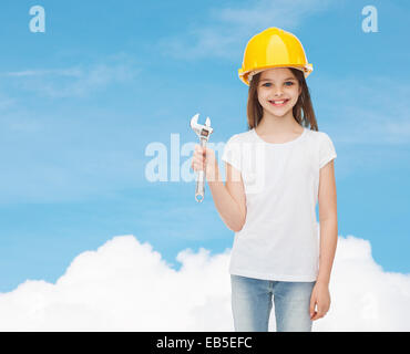 lächelnde Mädchen im Helm mit Schraubenschlüssel Stockfoto