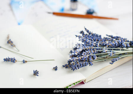 Nahaufnahme eines Bündels von Lavendel auf einem Notebook, auf weißen Tisch mit verschwommenen Kugelschreiber, Tinte, bunting Stockfoto