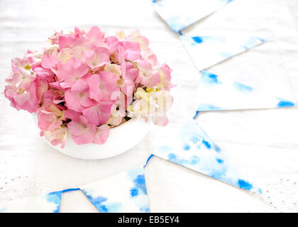 Rosa Hortensien in Schüssel weiß, blau und weiß auf Vintage weiße Tischdecke Girlande Stockfoto