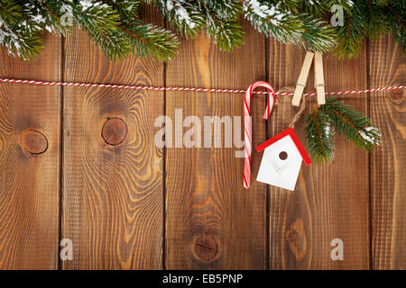 Schnee Tanne Baum und Weihnachten Dekoration am Seil über rustikalen Holzbrett mit Textfreiraum Stockfoto