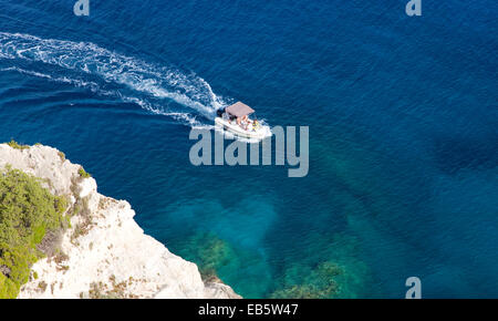 Korithi, Zakynthos, Ionische Inseln, Griechenland. Kleines Boot unter Klippen über den blauen Grotten bei Kap Skinari vorbei. Stockfoto