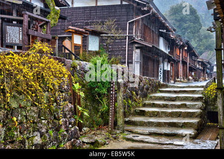 Blick auf die Terashita Straße in der Edo-Stadt Tsumago. Reihe von traditionellen Holzgebäuden, Geschäften und japanischen Gasthäusern, im strömenden Regen. Stockfoto