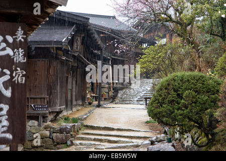 Blick auf die Terashita Straße in der Edo-Stadt Tsumago. Reihe von traditionellen Holzgebäuden, Geschäften und japanischen Gasthäusern, im strömenden Regen. Stockfoto