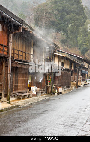 Blick auf die Terashita Straße in der Edo-Stadt Tsumago. Reihe von traditionellen Holzgebäuden, Geschäften und japanischen Gasthäusern, im strömenden Regen. Stockfoto