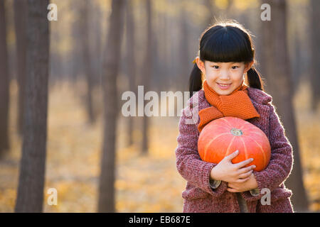 Kleines Mädchen hält einen Kürbis in herbstlichen Wälder Stockfoto