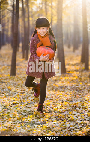 Kleines Mädchen hält einen Kürbis in herbstlichen Wälder Stockfoto