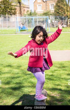 Fünf Jahre altes Mädchen, die versuchen, ihr Gleichgewicht zu halten auf einem Balken im Kinderspielplatz Stockfoto