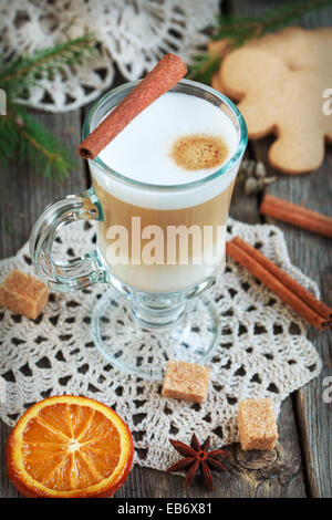 Heißen Kaffee mit Milch in ein Glas auf einem Holztisch mit Stücken von Zucker, Zimtstangen, kandierten Orangenscheibe Stockfoto