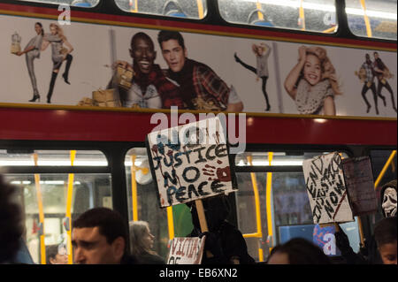 Zentral-London, UK. 26. November 2014. Demonstranten nehmen zu den Straßen von London nach der Demonstration vor der US-Botschaft, London, gegen die Entscheidung von einer Jury nicht Polizist Darren Wilson schießen tot Michael Brown, eine unbewaffnete 18-Year-Old, auf einer Seite Wohnstraße in Ferguson am 9. August in Rechnung zu stellen. Demonstranten skandierten "Hands UP nicht schießen" und "Wer ist unsere Straßen Straßen". Stockfoto