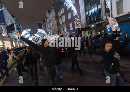 Zentral-London, UK. 26. November 2014. Demonstranten nehmen zu den Straßen von London nach der Demonstration vor der US-Botschaft, London, gegen die Entscheidung von einer Jury nicht Polizist Darren Wilson schießen tot Michael Brown, eine unbewaffnete 18-Year-Old, auf einer Seite Wohnstraße in Ferguson am 9. August in Rechnung zu stellen. Demonstranten skandierten "Hands UP nicht schießen" und "Wer ist unsere Straßen Straßen". Stockfoto