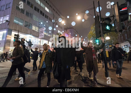 Zentral-London, UK. 26. November 2014. Demonstranten nehmen zu den Straßen von London nach der Demonstration vor der US-Botschaft, London, gegen die Entscheidung von einer Jury nicht Polizist Darren Wilson schießen tot Michael Brown, eine unbewaffnete 18-Year-Old, auf einer Seite Wohnstraße in Ferguson am 9. August in Rechnung zu stellen. Demonstranten skandierten "Hands UP nicht schießen" und "Wer ist unsere Straßen Straßen". Stockfoto