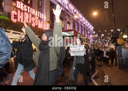 Zentral-London, UK. 26. November 2014. Demonstranten nehmen zu den Straßen von London nach der Demonstration vor der US-Botschaft, London, gegen die Entscheidung von einer Jury nicht Polizist Darren Wilson schießen tot Michael Brown, eine unbewaffnete 18-Year-Old, auf einer Seite Wohnstraße in Ferguson am 9. August in Rechnung zu stellen. Demonstranten skandierten "Hands UP nicht schießen" und "Wer ist unsere Straßen Straßen". Stockfoto