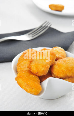 eine Schüssel mit Hähnchen-Nuggets auf einem gedeckten Tisch Stockfoto