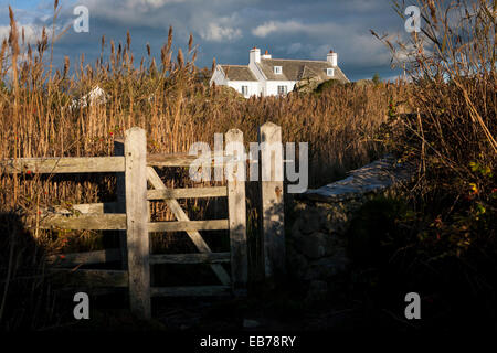 Gebäude von Cae Llyn, Anglesey, North Wales, an einem sonnigen Abend betrachtet das hölzerne Tor eines angrenzenden öffentlichen Fußweg Stockfoto