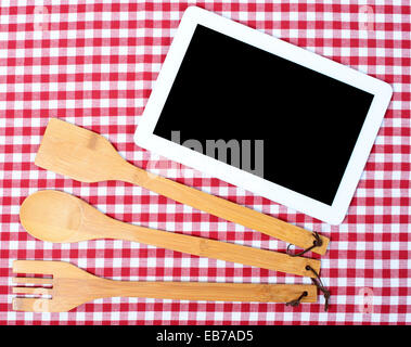 Digital-Tablette mit hölzernen Besteck auf rote und weiße Serviette Stockfoto