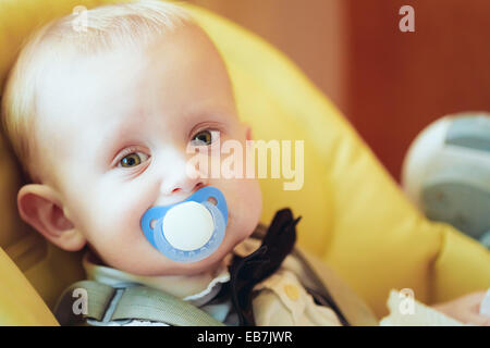 Pretty Baby Boy mit großen grünen Augen sitzen gelbe mit Schnuller Stockfoto