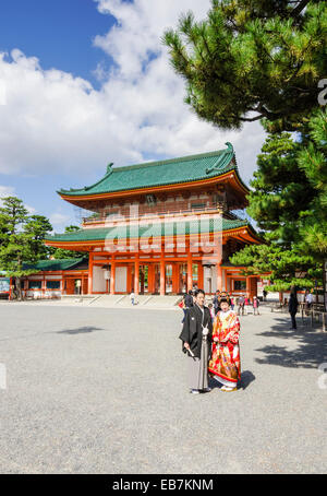 Traditionell gekleidete Paar posieren vor dem Haupttor zum Heian-Schrein, Kyoto, Kansai, Japan Stockfoto