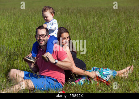 Eine glückliche Familie, eine schwangere Frau mit ihrem Mann und kleiner Junge Zeit miteinander verbringen und spielen in einer Sommerwiese Stockfoto