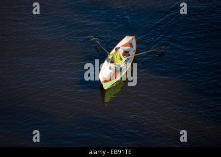 Luftaufnahme eines älteren Mannes, der ein kleines Fiberglas-Boot / Schiff / Beiboot rudert, Finnland Stockfoto