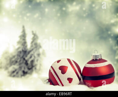 Roter Weihnachtsschmuck vor Schnee kauerte Kiefern Stockfoto