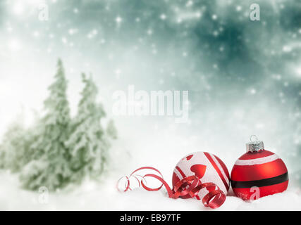 Roter Weihnachtsschmuck vor Schnee kauerte Kiefern Stockfoto