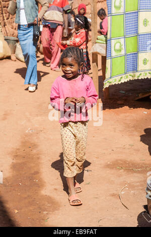 Junge einheimische afrikanische Mädchen mit geflochtenen Haaren, die zu Fuß in einer unbefestigten Straße in Antananarivo oder Tana, Hauptstadt Madagaskars Stockfoto