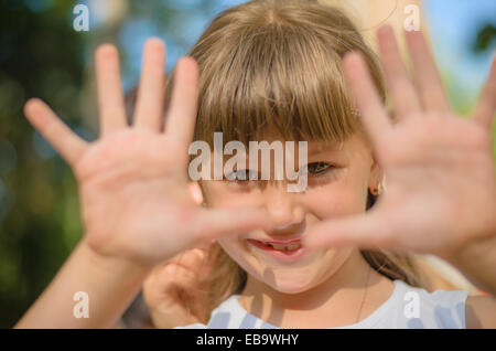 Lächelndes Mädchen zeigt ihre Hände bilden einen Rahmen Stockfoto