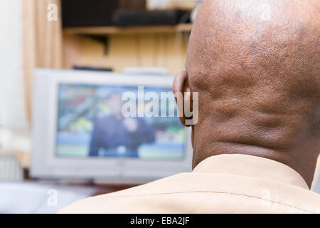 Älterer Mann zu Hause vor dem Fernseher sitzen Stockfoto