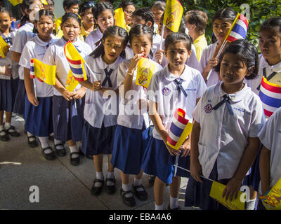 Bangkok, Bangkok, Thailand. 28. November 2014. Schulkinder mit Thai Fahnen und die gelbe Flagge der thailändischen Monarchie Linie bis zu Angebot Geburtstagswünsche für Bhumibol Adulyadej, der König von Thailand. Der König wurde am 5. Dezember 1927, in Cambridge, Massachusetts geboren. Die Familie war in den Vereinigten Staaten, weil sein Vater, Prinz Mahidol, Public Health an der Harvard University studierte. Hat der seit 1946 regiert und herrscht weltweit derzeit längste Umhüllung Monarch und der längste Umhüllung Monarch in der thailändischen Geschichte. Bhumibol, der in einem schlechten Gesundheitszustand ist, wird durch das thailändische Volk verehrt. Seine birthd Stockfoto