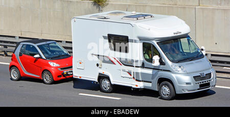 Seitenansicht und Vorderansicht Wohnmobil Wohnmobil Wohnmobil mit rotem Smart Fortwo Auto auf der Autobahn M25 London Orbitalstraße Essex England Großbritannien Stockfoto