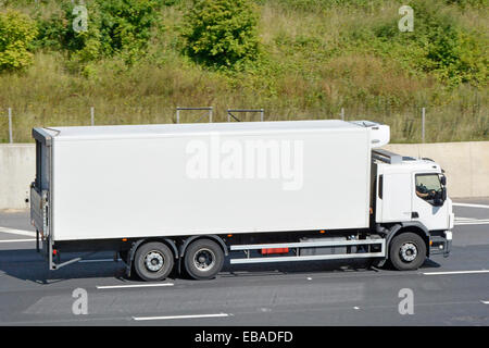 Fahrer im Fahrerhaus bei der Arbeit weiß sauberes, unbeschriftetes Doppelhinterachsen-Lkw mit starrer Karosserie, Seitenansicht, Fahren auf der m25-Autobahn Essex England Großbritannien Stockfoto