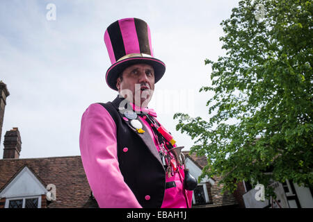 Nahaufnahme einer Straße Entertainer auf Stelzen, tragen helle Kleidung und einen Zylinderhut auf der Charta Messe in Haslemere. Stockfoto