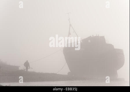 Loch Linnhe Schottland, Großbritannien. 28. November 2014. Eine einsame Gestalt bewundert die gestrandeten Fischerboot am Ufer des Loch Linnhe bei schweren Morgennebel Credit: Kenny Ferguson/Alamy Live News Stockfoto