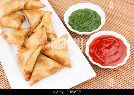 Draufsicht der köstlichen tief gebraten südindische Samosas mit Minze-Chutney und Tomatensauce. Stockfoto