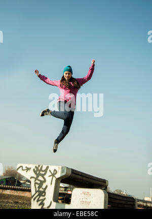 Teenager-Mädchen springen über Bank im Freien, Industriegebiet, Mannheim, Deutschland Stockfoto