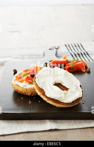 Geröstetem Sesam-Samen-Bagel mit Frischkäse, Räucherlachs, Dill und Kapern auf Holz Schneidebrett, Studioaufnahme gekrönt Stockfoto