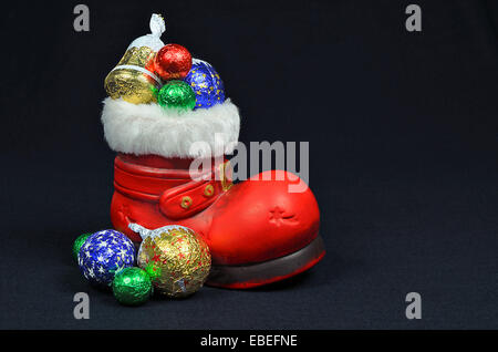 Santa rote Stiefel mit Süßigkeiten, Nahaufnahme, auf schwarzem Hintergrund isoliert Stockfoto