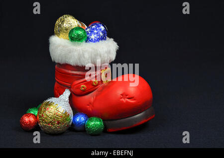 Santa rote Stiefel mit Süßigkeiten, Nahaufnahme, auf schwarzem Hintergrund isoliert Stockfoto