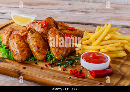 gebratene Hähnchenflügel mit roter Sauce und Pommes frites Stockfoto