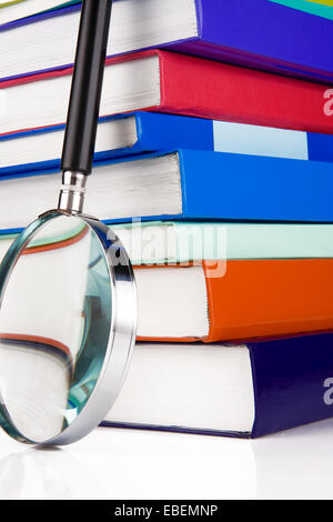 Stapel von Büchern und Lupe isoliert auf weißem Hintergrund Stockfoto