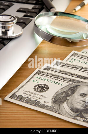Stethoskop auf Tastatur und US-Dollar mit Stift auf Holztisch Stockfoto