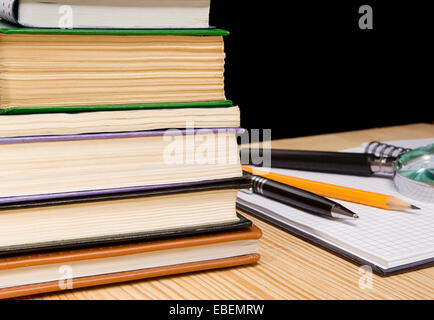 Stapel von Büchern und Kugelschreiber mit Bleistift auf Holztisch Stockfoto